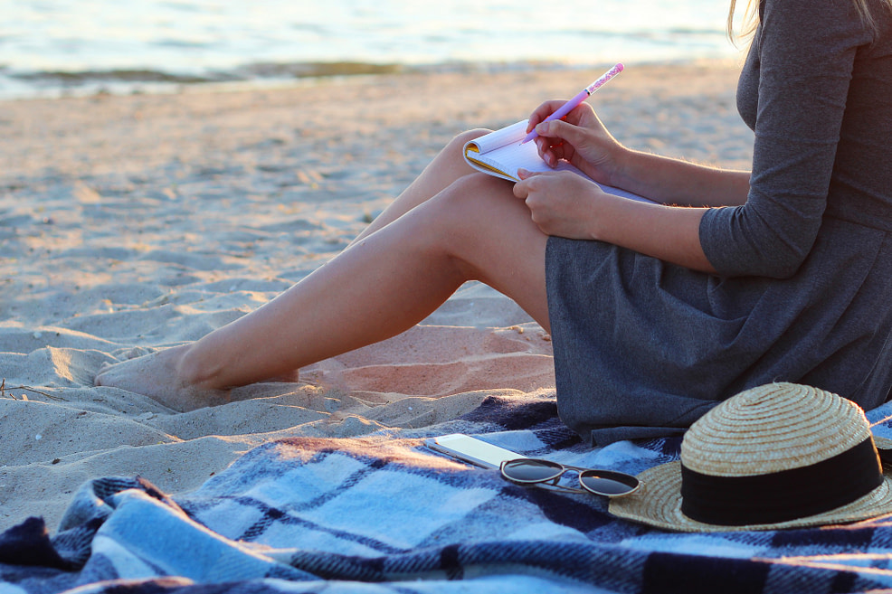 Uncovering the Real Self Girl writing on notepad by the beach uncovering her true self