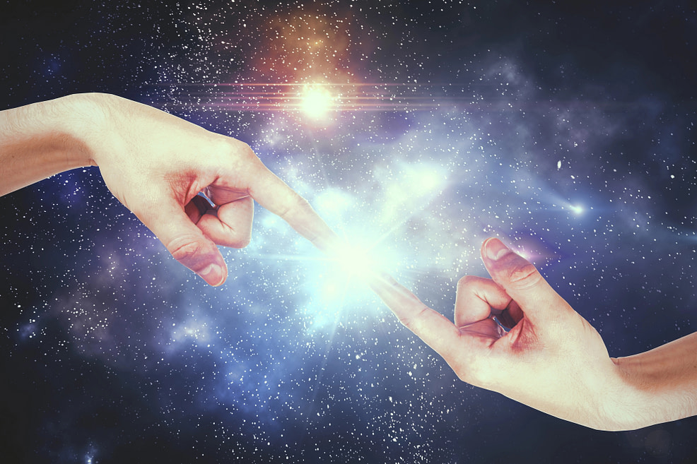 Universal oneness Hands with fingers touching, lighting up at contact with galaxy background