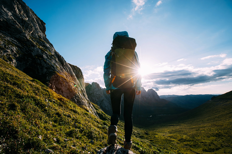 Possibilities Woman backpacker hiking on sunset alpine mountain peak, portraying possibilities through life’s uncertainties.