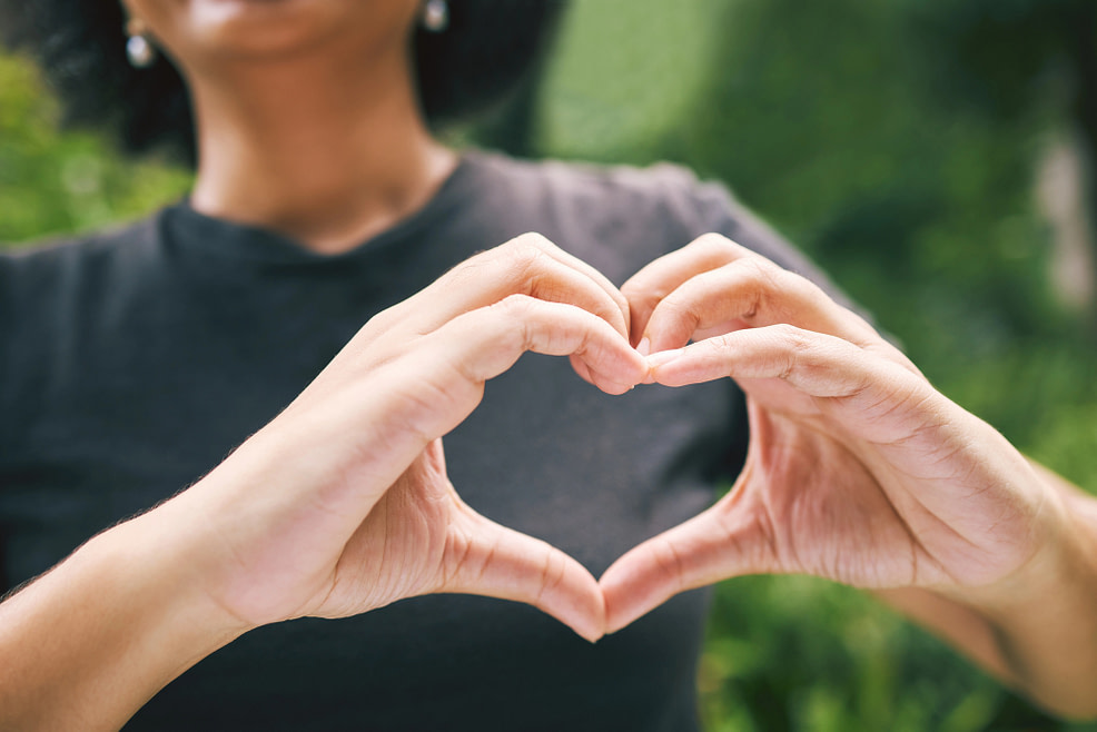 Woman outside making heart shape with hands 