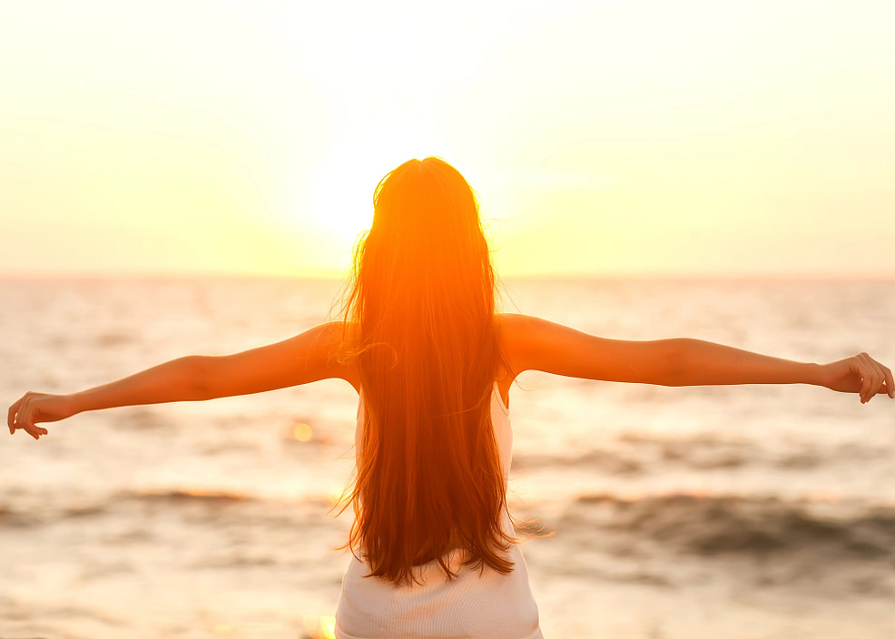 Embodied and free woman with arms outstretched on the beach at sunset
