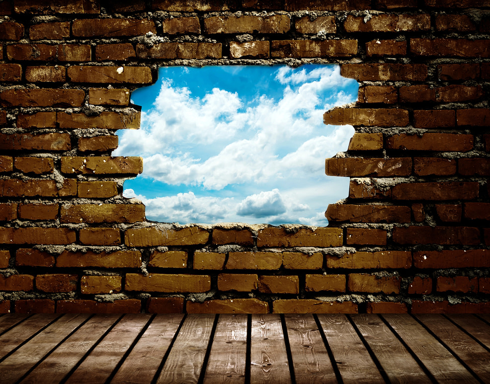 Broken Wall Hole in a wall to a blue sky representing the path forward