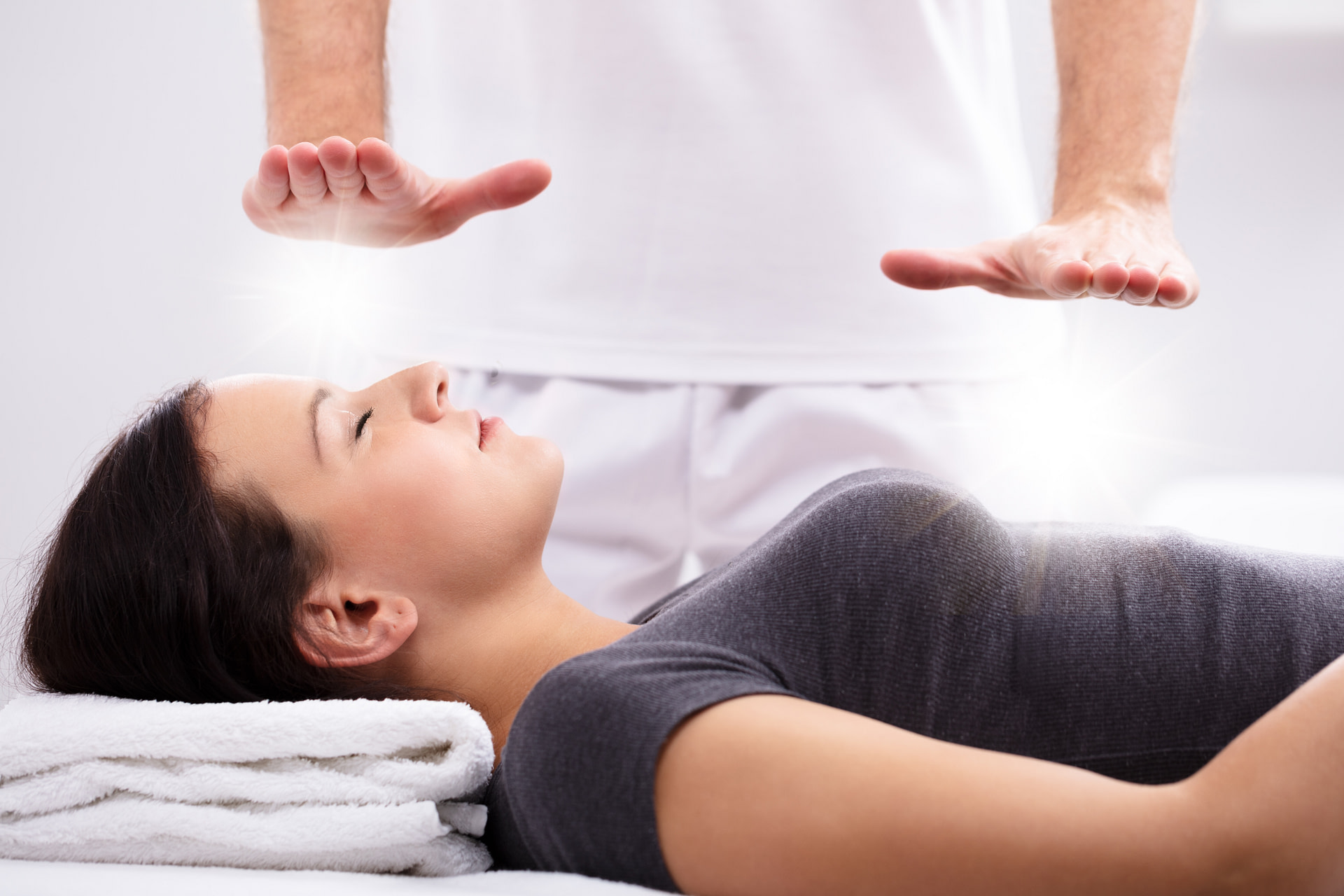 Young Woman Receiving Reiki Treatment By Reiki Practitioner