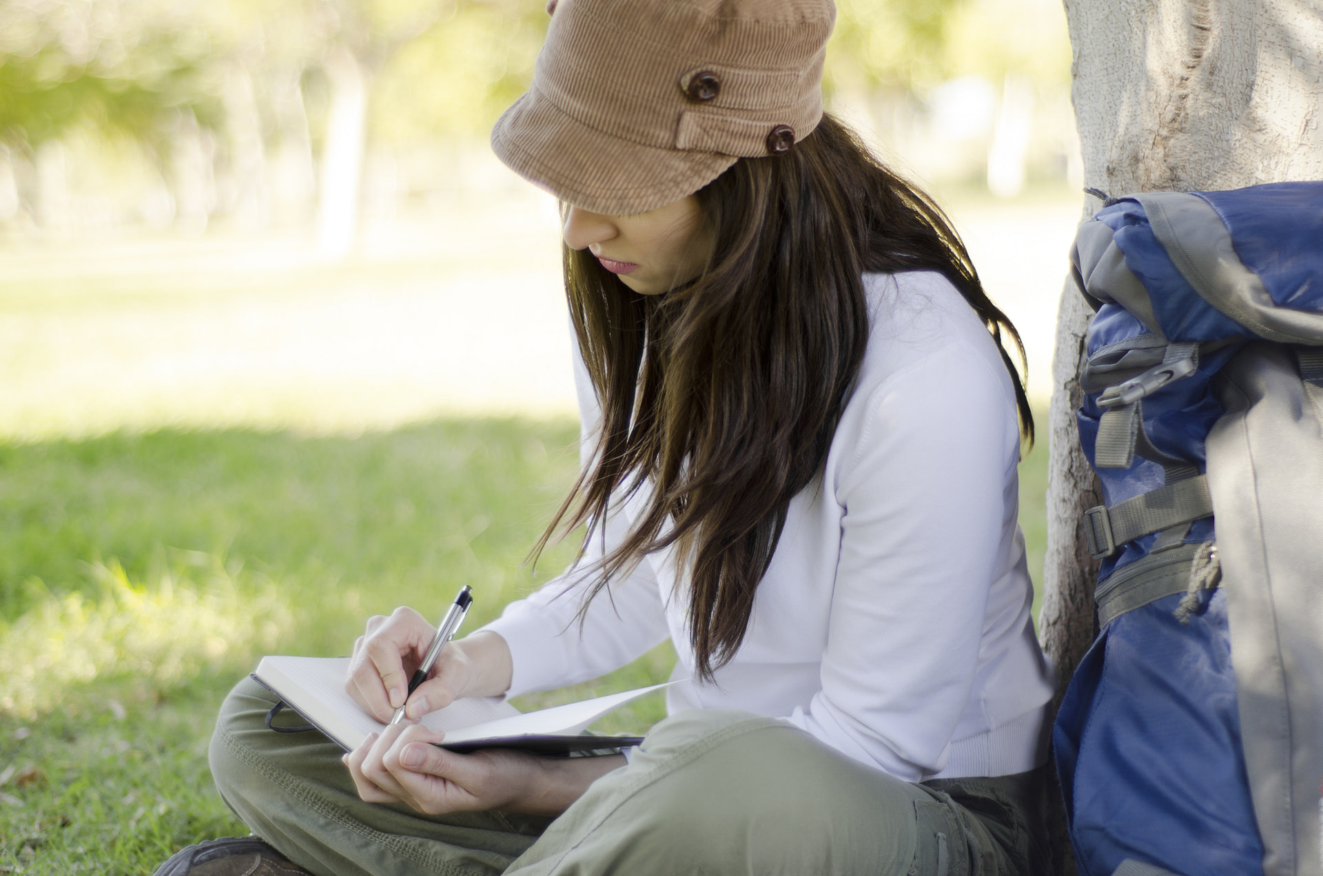 Woman sitting outside reflecting, writing in journal