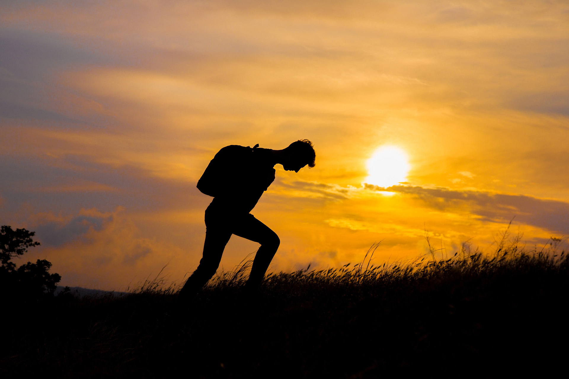 silhouette walking in front of sunset-feeling exhausted
