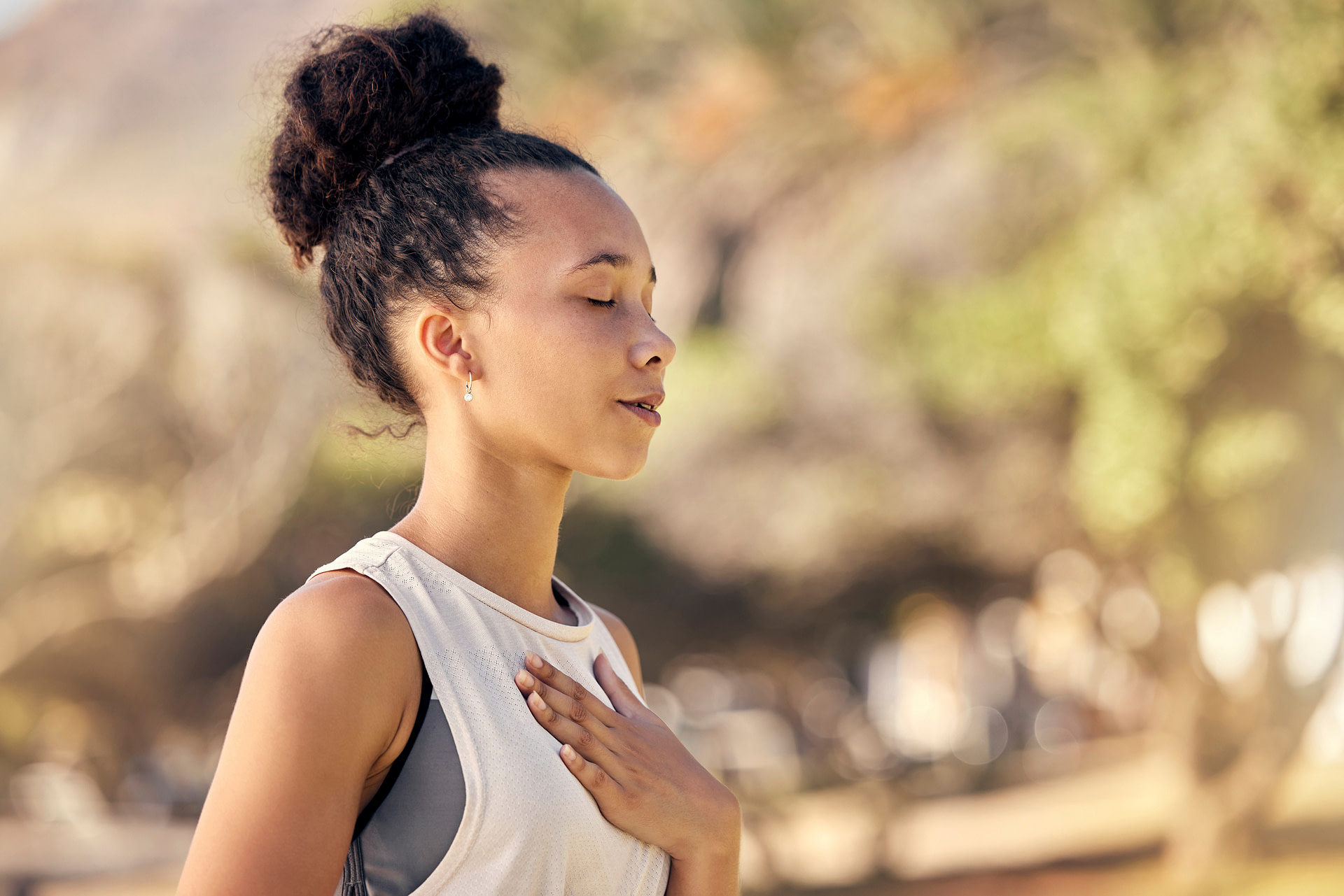 Woman standing outside with eyes closed and hand on heart