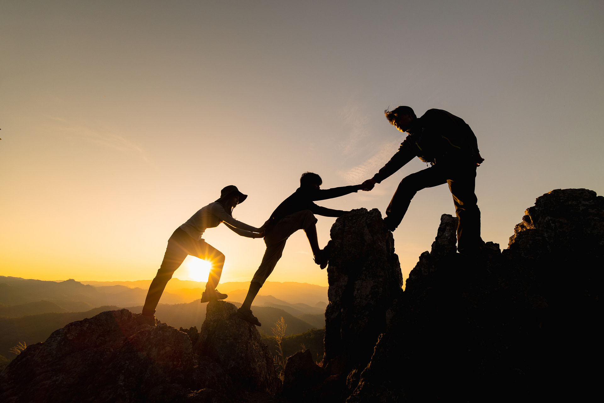 silhouette of hikers climbing up a mountain cliff to represent support
